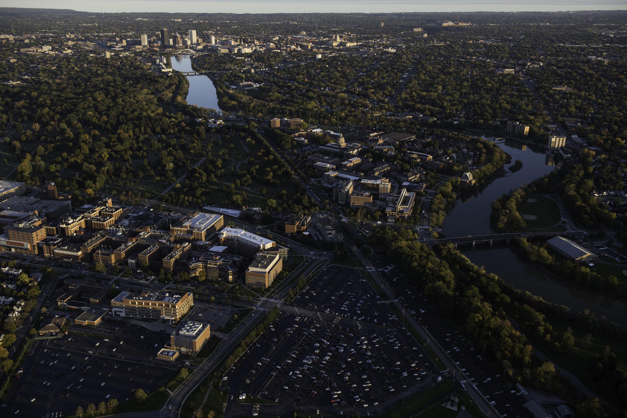 Aerial photo of University of Rochester's River Campus, Medical Center and downtown Rochester, NY alongside the Genesee River in evening